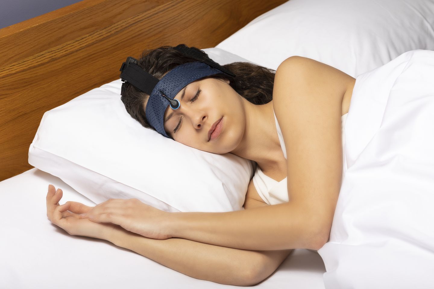 Eine Frau liegt schlafend im Bett, um den Kopf trägt sie ein Stirnband, das ihren Schlaf misst.