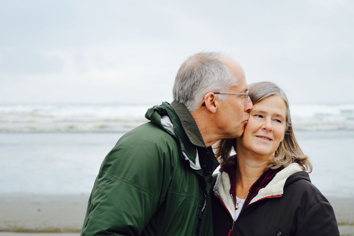 Ein Mann und eine Frau in ihren Sechsziger-Jahren als glückliches und zufriedenes Paar am Strand an einem Herbsttag.