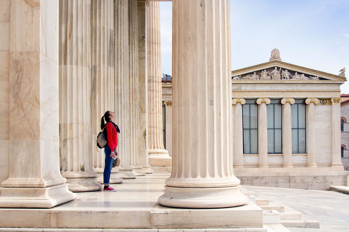 A young woman stands on the canopy of an ancient temple and looks up.