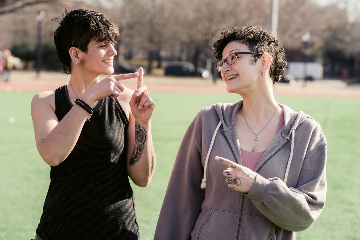 Two women have a non-verbal conversation with hand signs. 