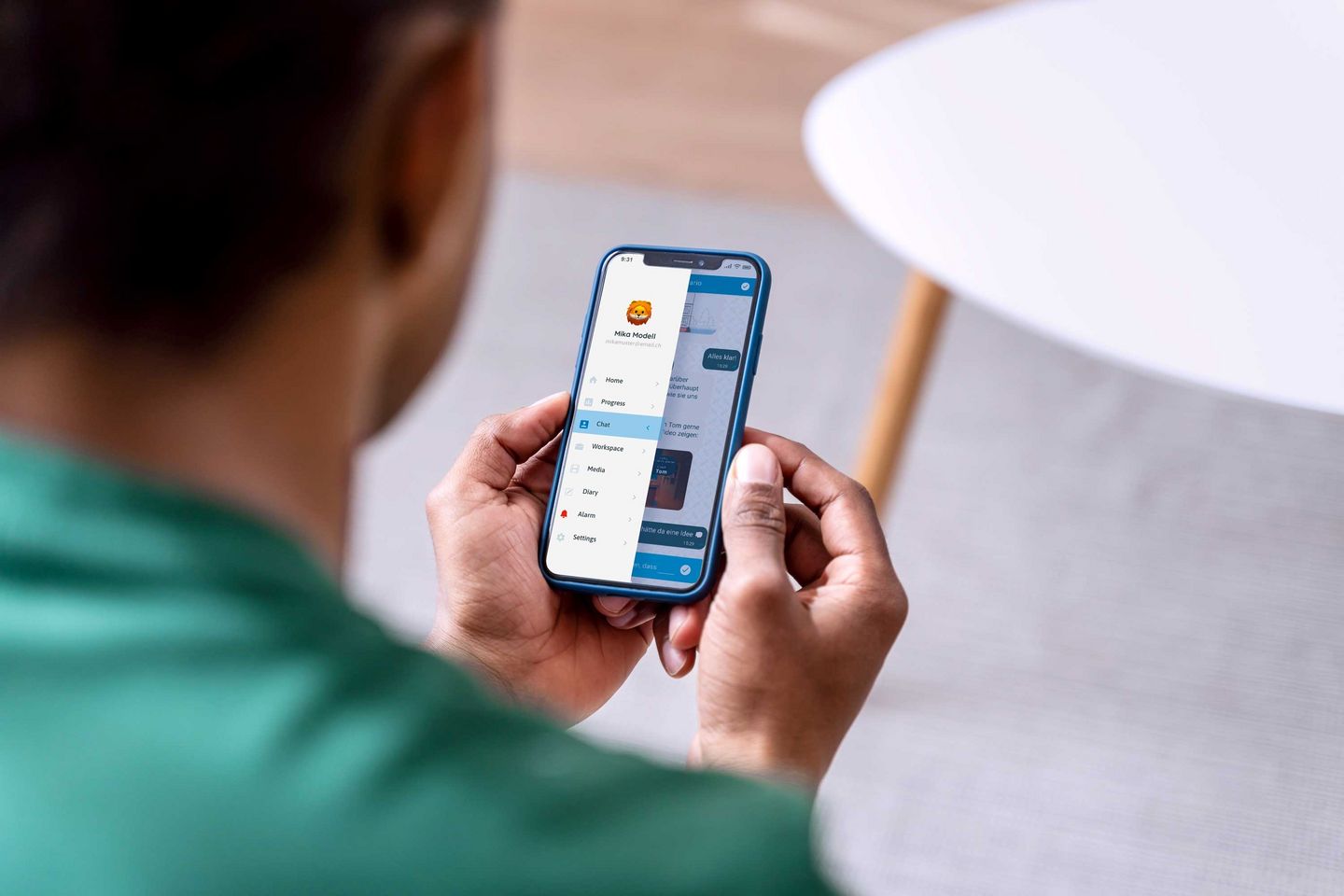 Ein Blick über die Schultern eines jungen Mannes, der ein Smartphone in den Händen hält, auf dessen Display die geöffnete App zu sehen ist.