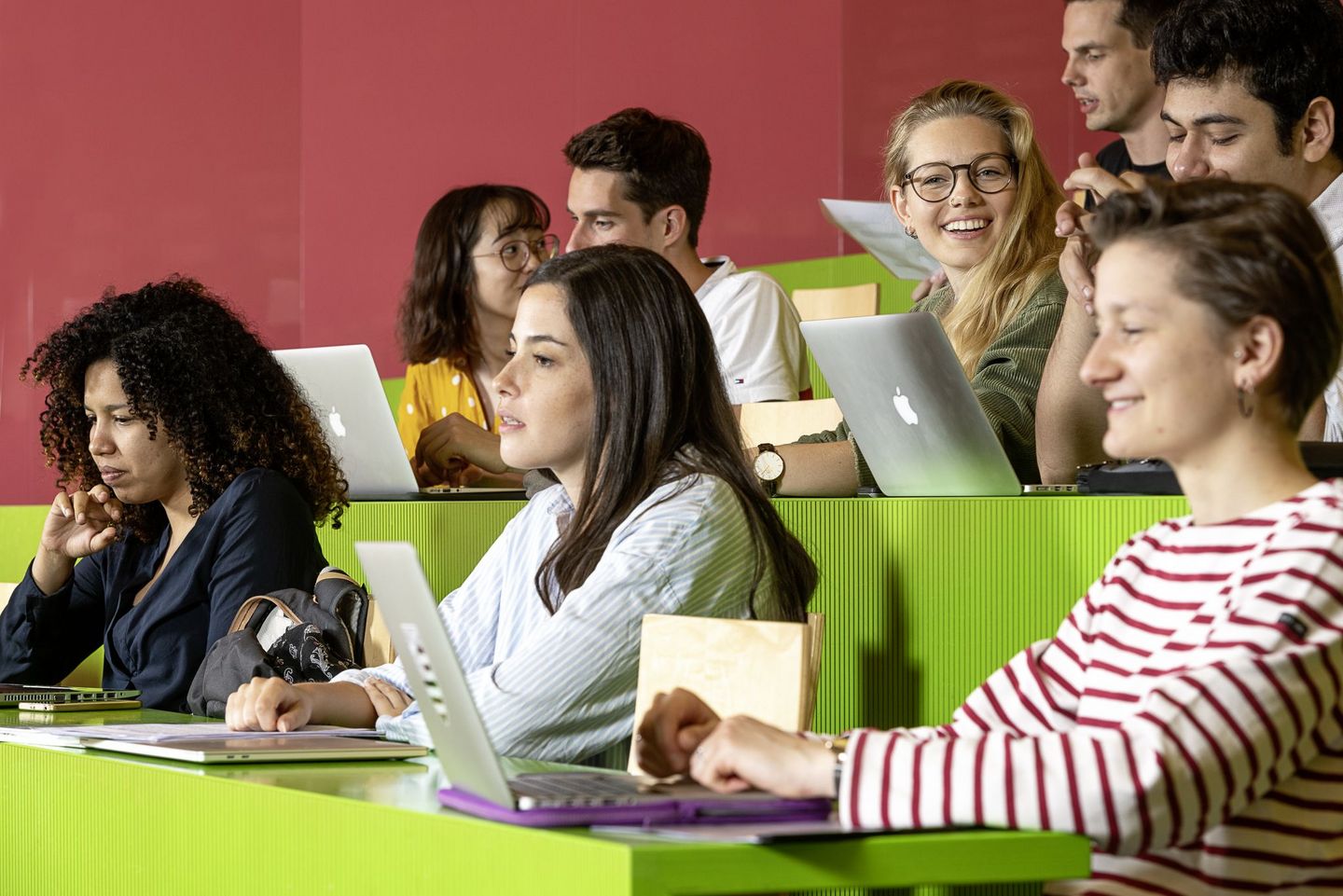 Several students are sitting in the lecture hall watching a lecture.